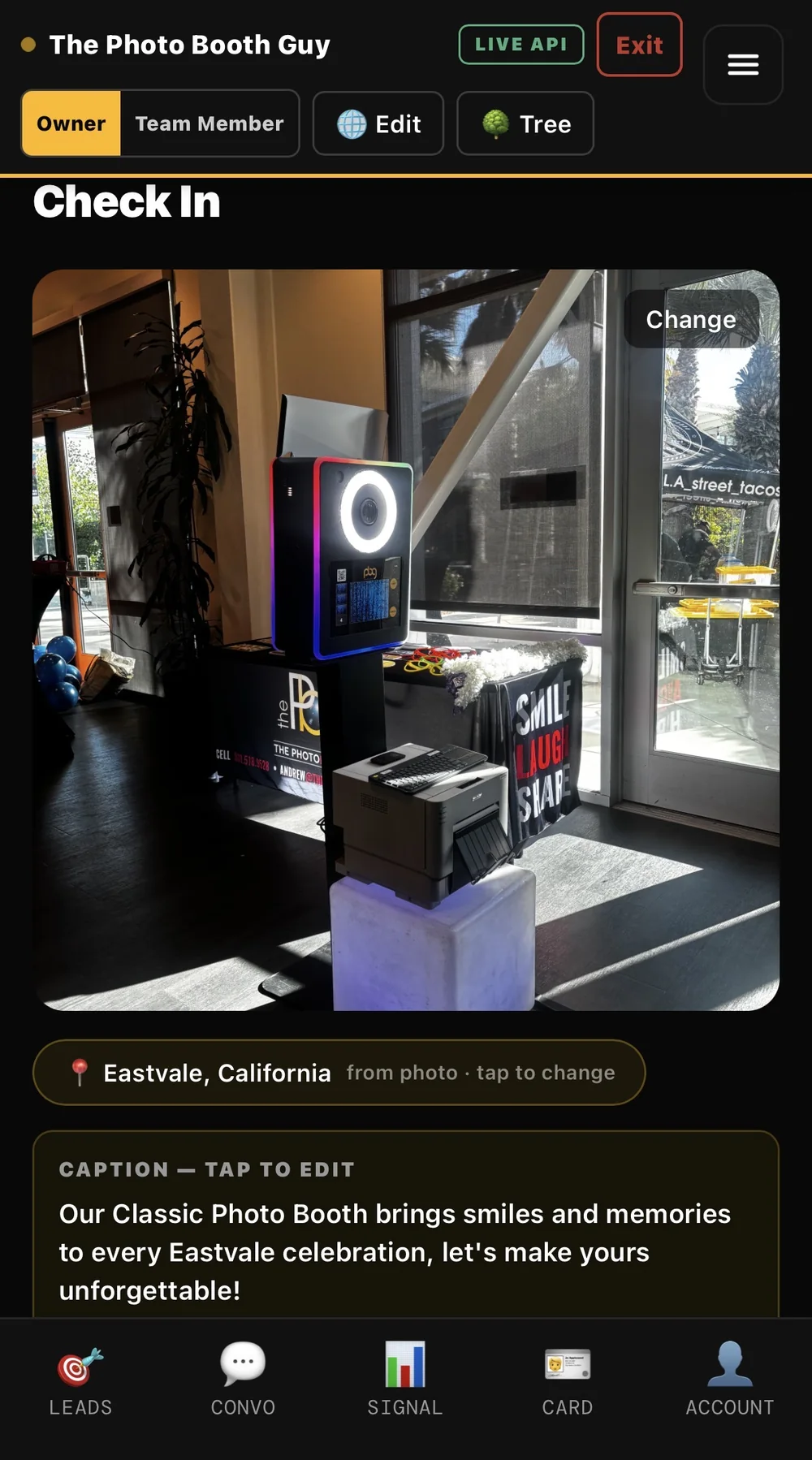 The HoneyBun Check In screen for The Photo Booth Guy: a photo of the booth setup, Eastvale, California read from the photo, a written caption, and the bottom tab menu