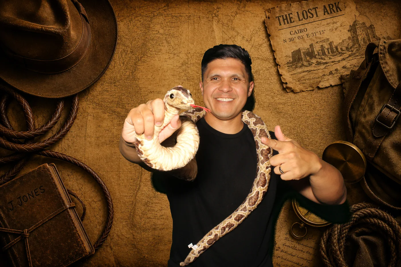 Booth photo of the founder of The Photo Booth Guy holding a snake, on an adventure-map backdrop